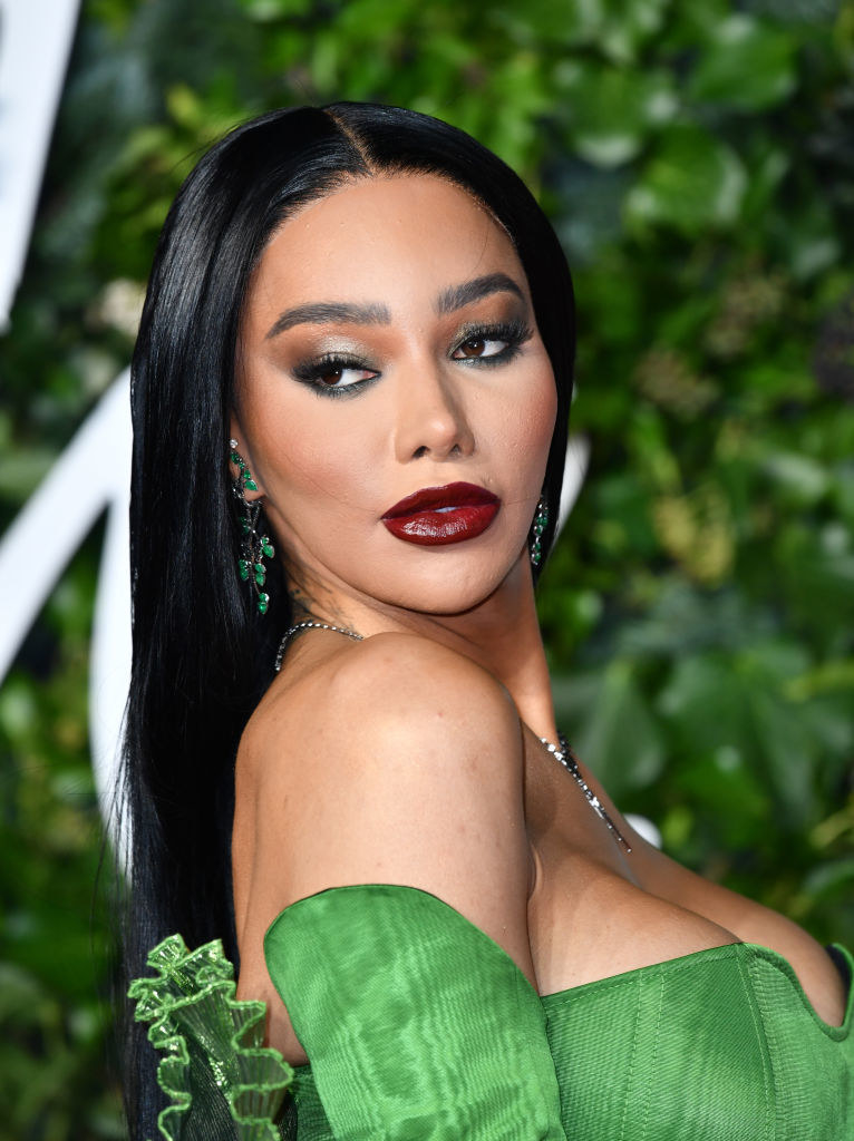 Munroe poses on a red carpet in full makeup and a strapless outfit
