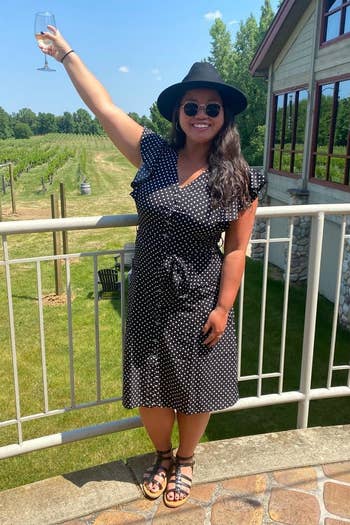 a reviewer wears the dress in black while holding a wine glass