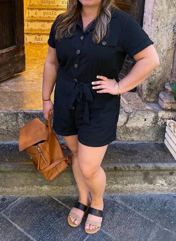 a reviewer wearing the black romper with sandals
