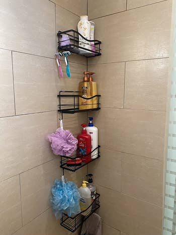 set of four black suction shower caddies with soap, shampoo, conditioner, and loofahs in corner of shower