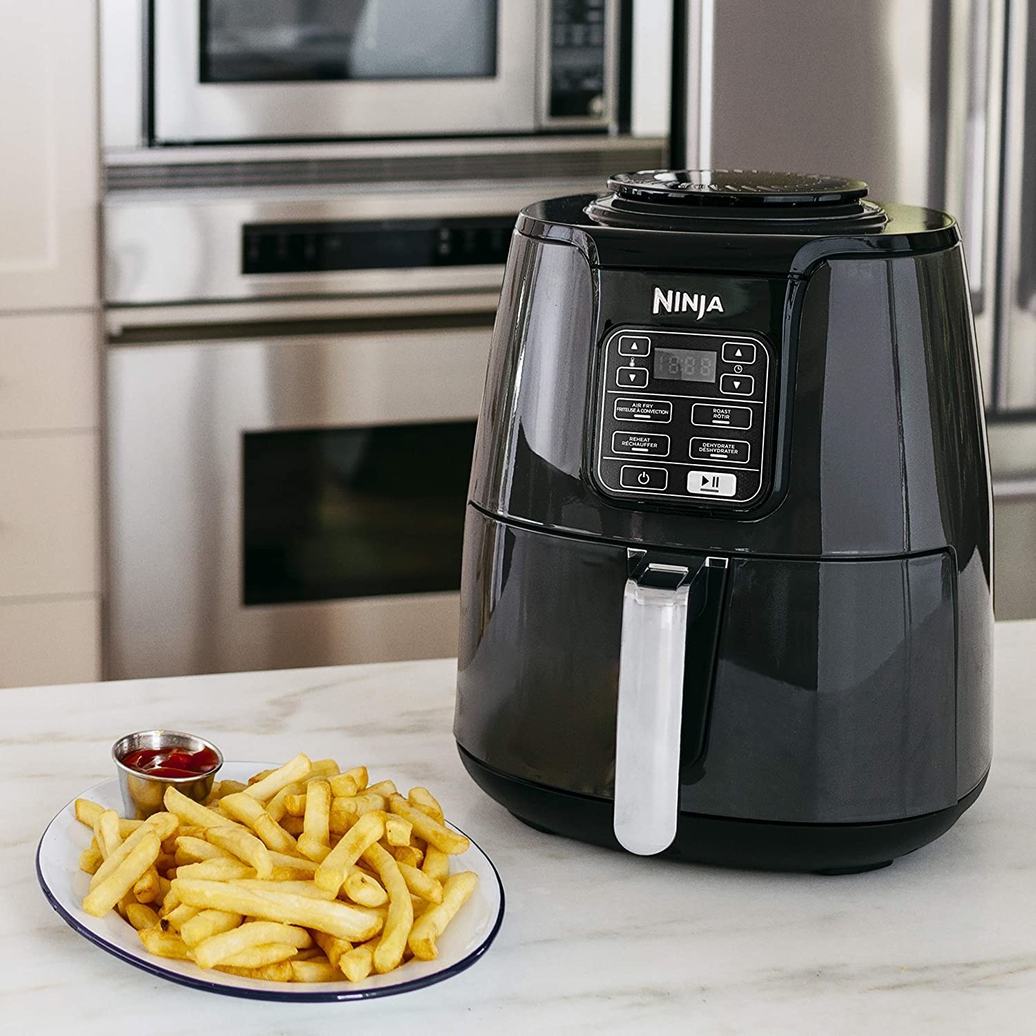 The air fryer next to a plate of fries