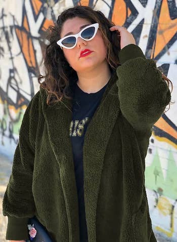 Model wearing the dark green hooded cardigan in front of a graffiti wall