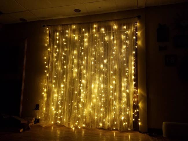reviewer photo of the string lights hung with curtains
