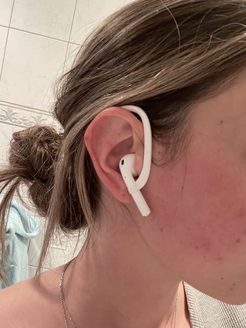 reviewer wears the white AirPod hooks over ears while wearing AirPods to gym