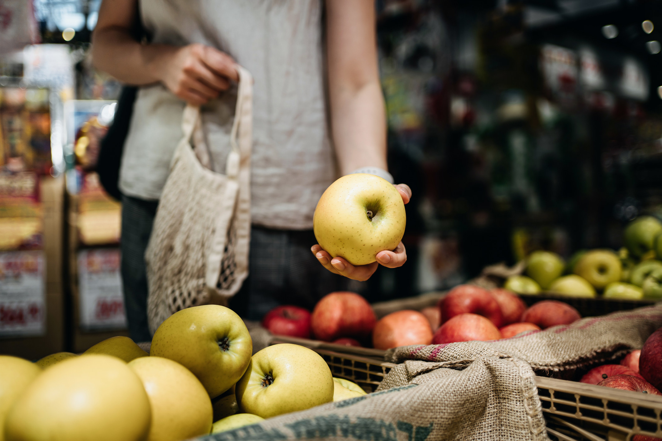 A person picking up an apple at the grocery store