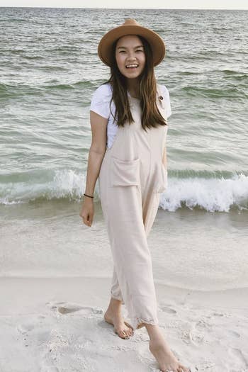 a reviewer wears the tan jumpsuit at the beach