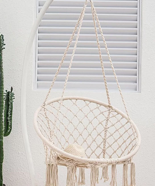 A hanging macrame chair hammock with falling tassles underneath