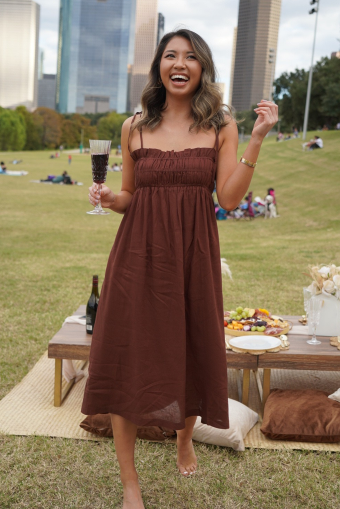 a model wears the brown dress outside in a park