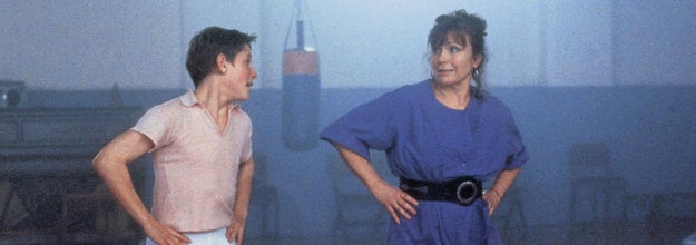 Billy Elliot and Mrs. Wilkinson are looking at each other while dancing.