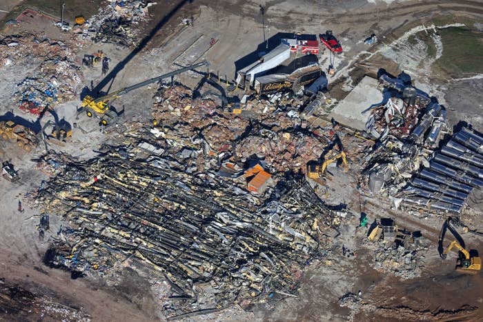 An aerial view shows rubble, cranes, trucks, and bulldozers
