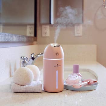 the pink facial humidifier emitting a mist out of the top