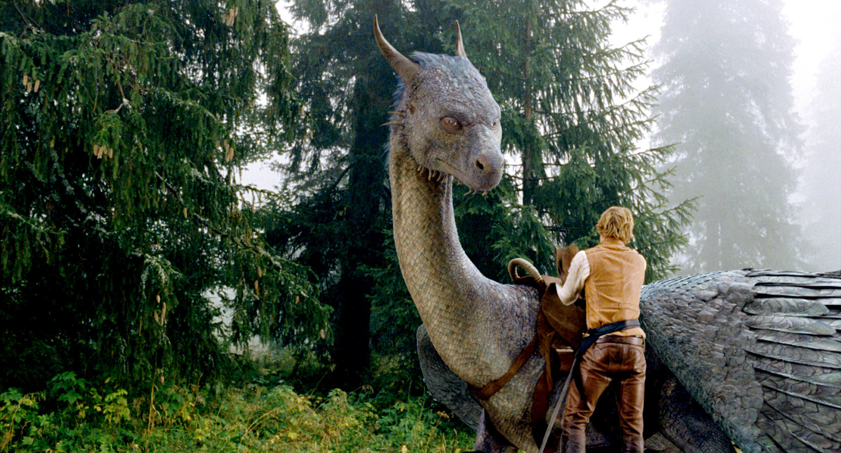 Edward Speleers putting a saddle on a dragon