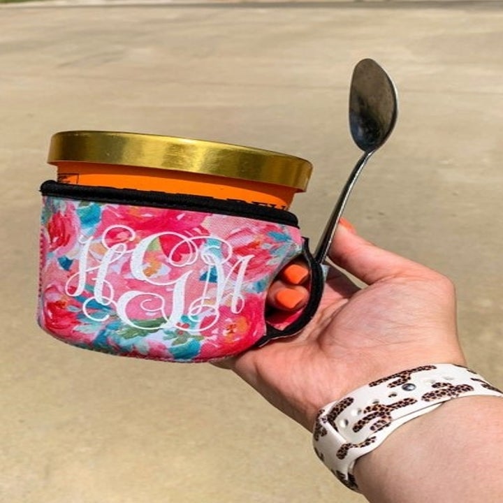 a model holding a rainbow pint cozy with a printed "HGM" monogram