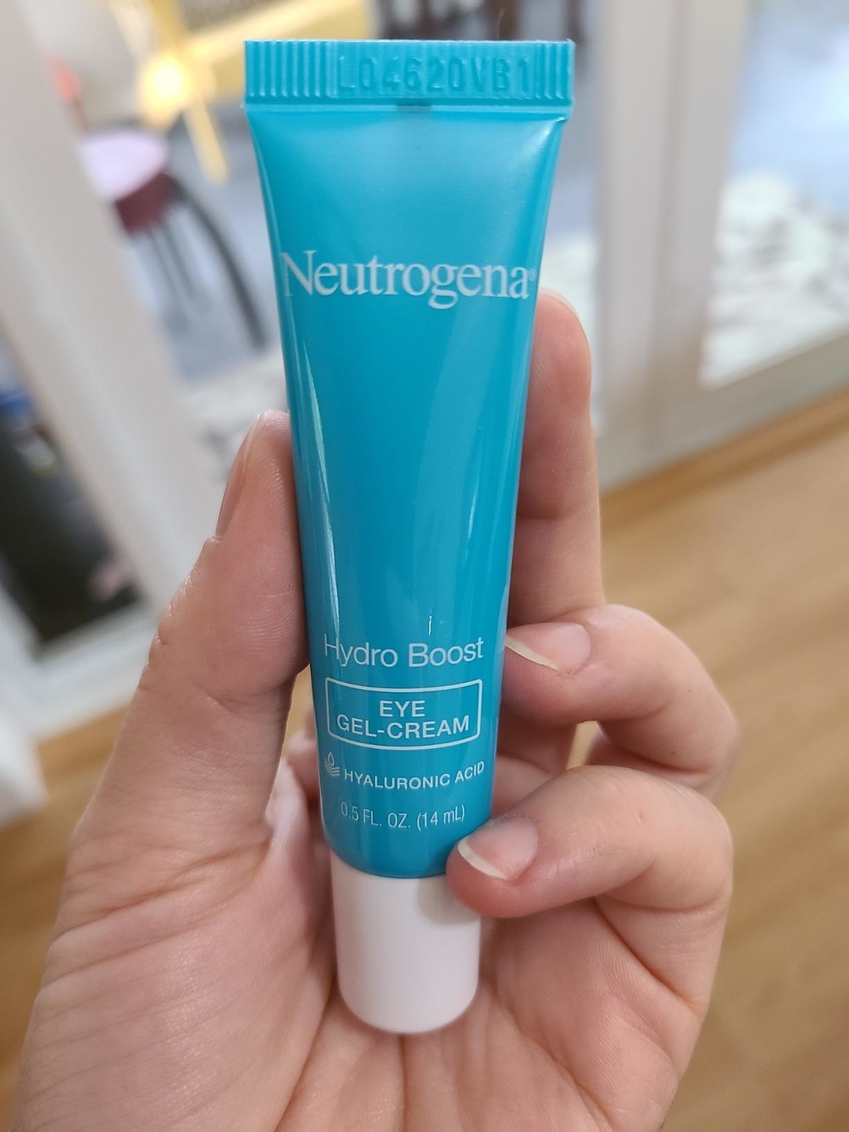 Reviewer holding blue and white eye cream bottle that reads &quot;Neutrogena hydro boost&quot;