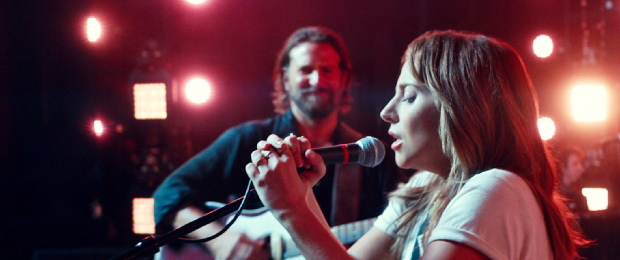 Lady Gaga singing with Bradley Cooper behind her