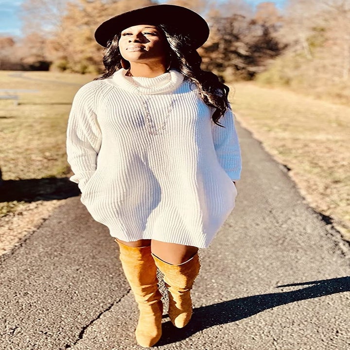 Reviewer wearing the white turtleneck dress with knee-high boots