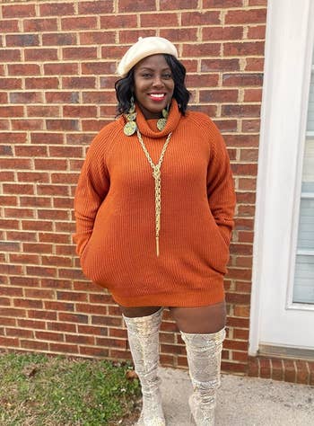 Reviewer wearing the orange turtleneck dress with thigh-high boots