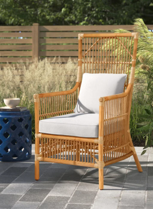 A wooden frame armchair with cushions. Has spindle-like detail and includes a throw pillow for the back.
