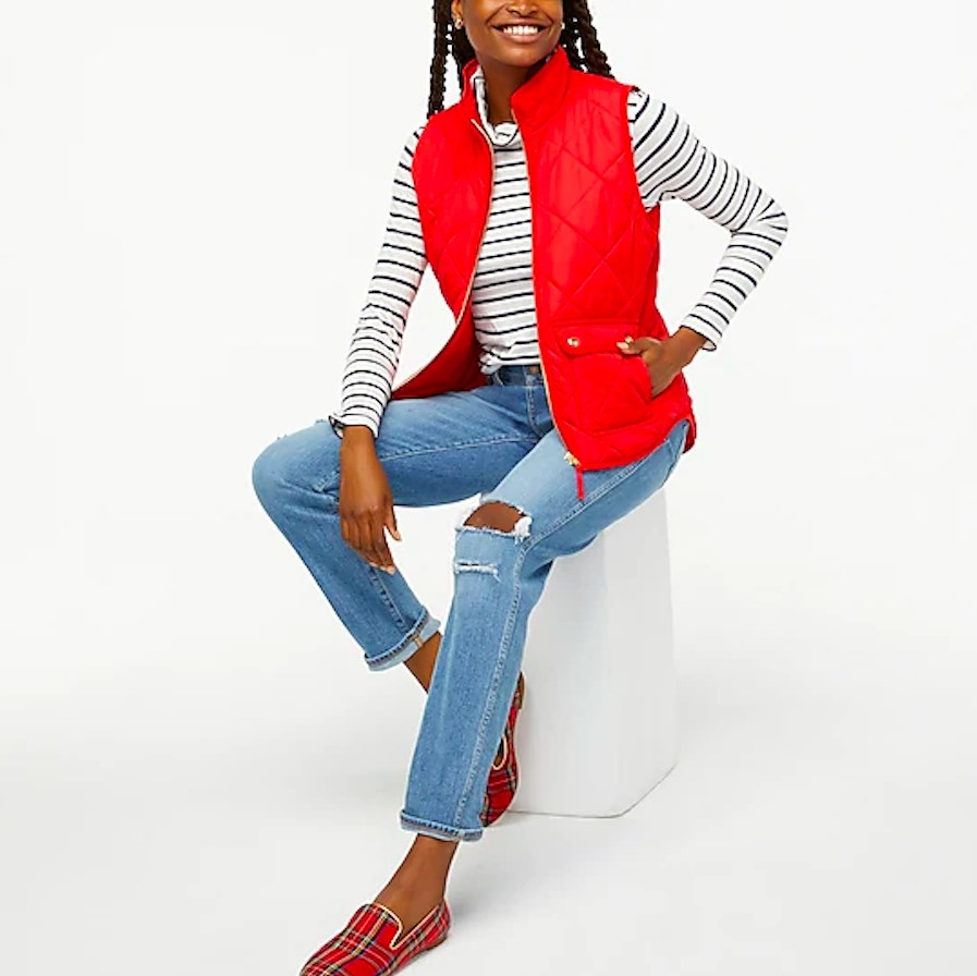 Model wearing red vest, jeans, striped shirt and plaid shoes