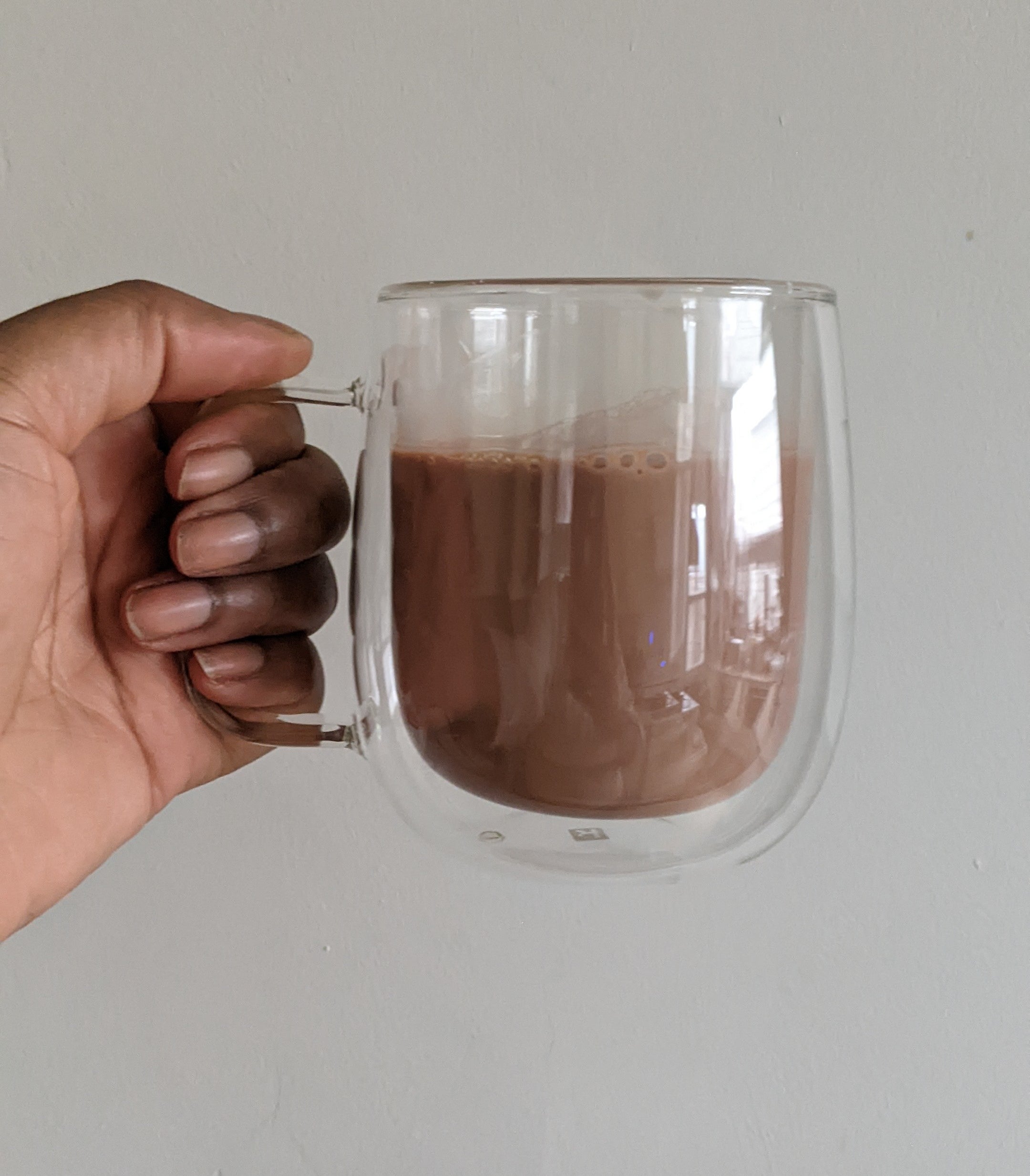 Kaysey holding a large glass mug filled with hot chocolate