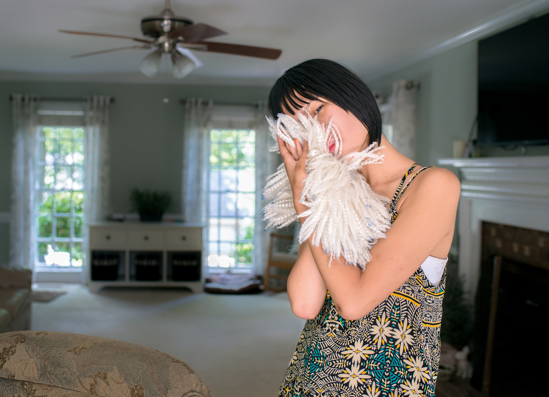 Mia, a young autistic person, stands in a room and presses her face into a soft, billowy mound of fabric