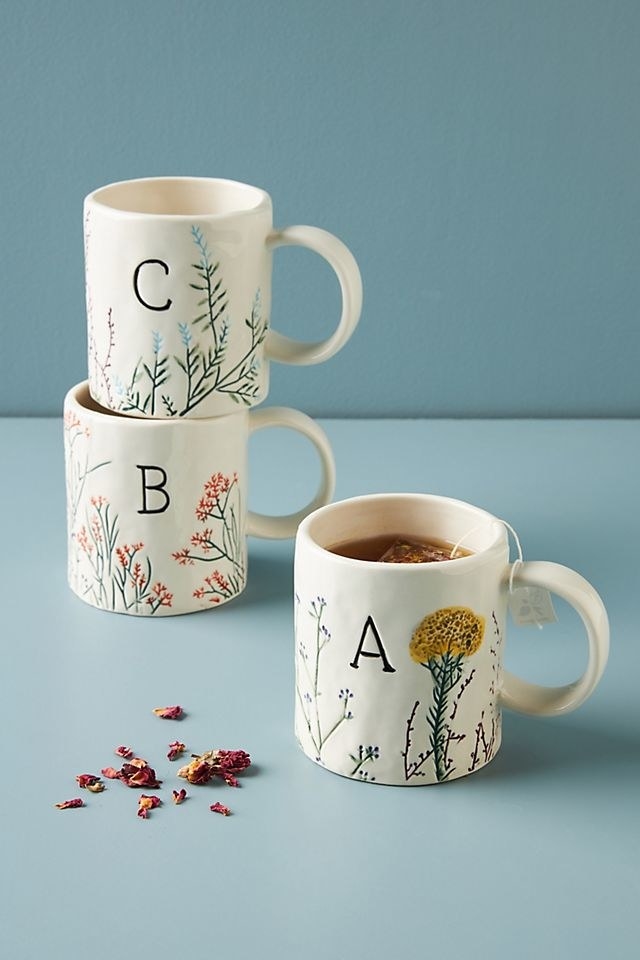 off-white mugs with colorful florals and medium-size black serif letters