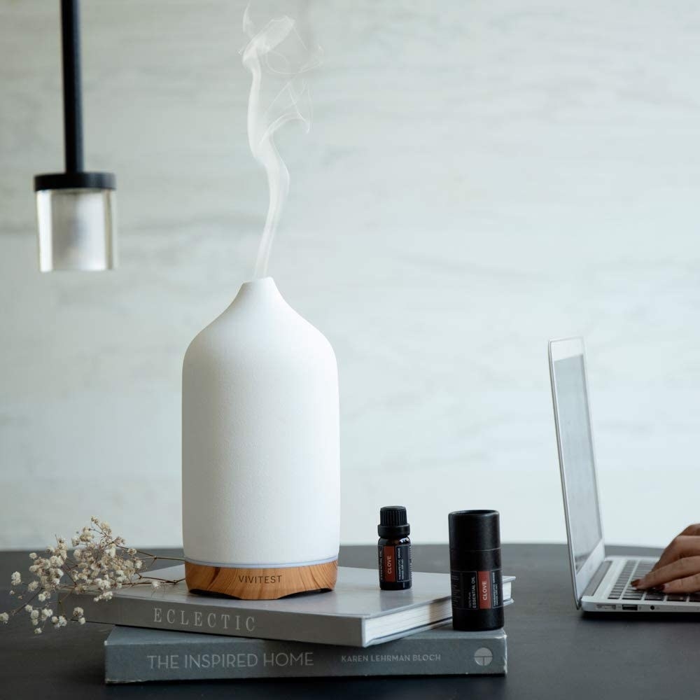 White ceramic oil diffuser on top of stack of books