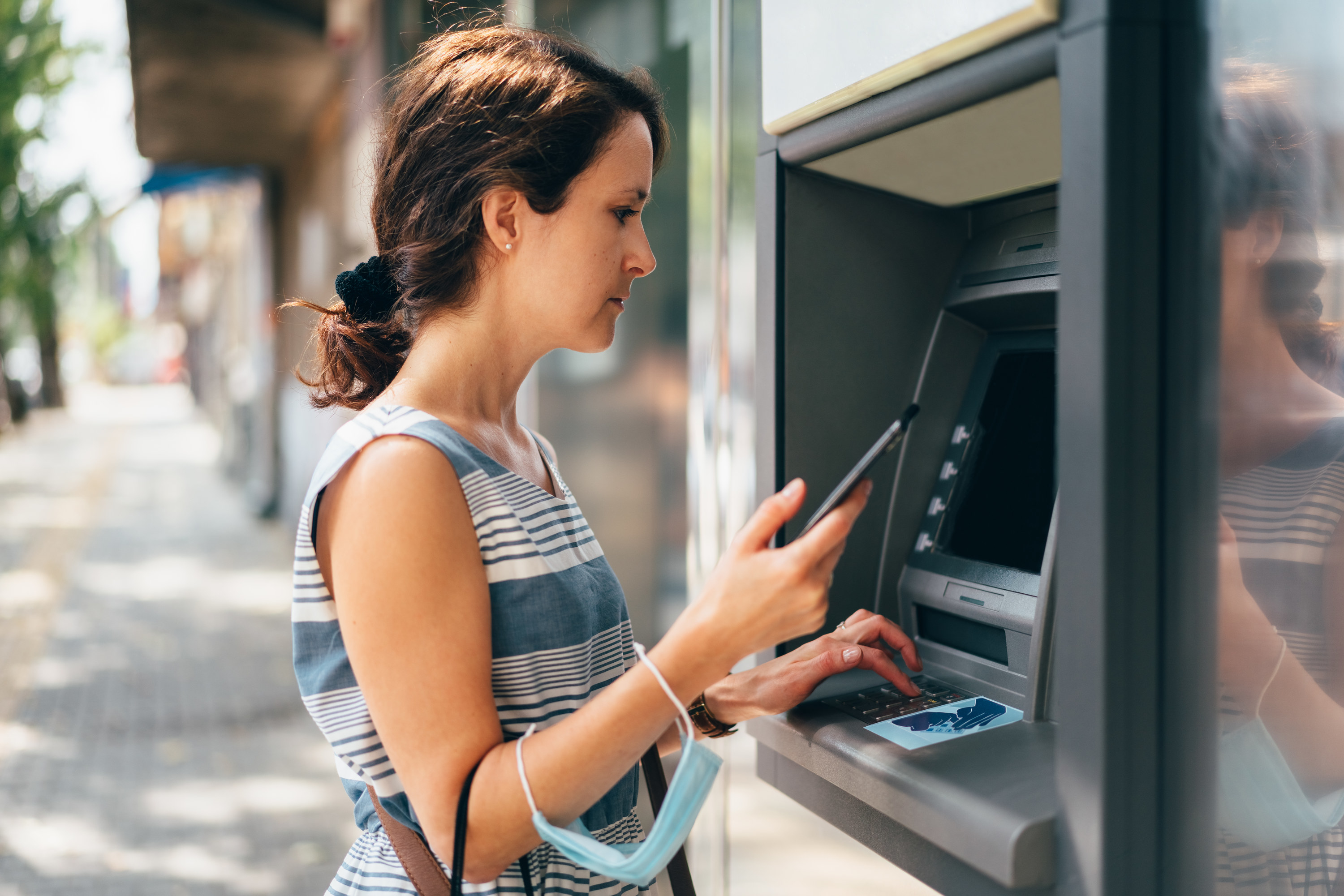 Woman at ATM with her phone