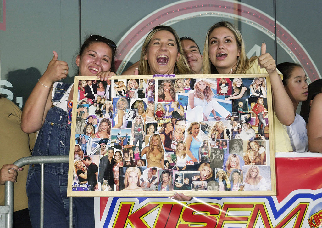 a group of girls hold up a sign with tiny pictures of jessica simpson
