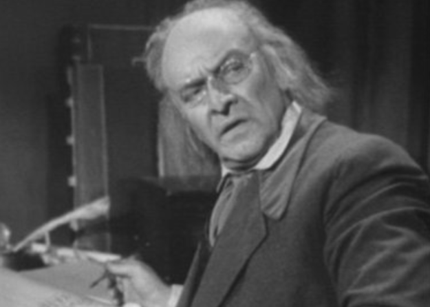 Scrooge writing at his desk