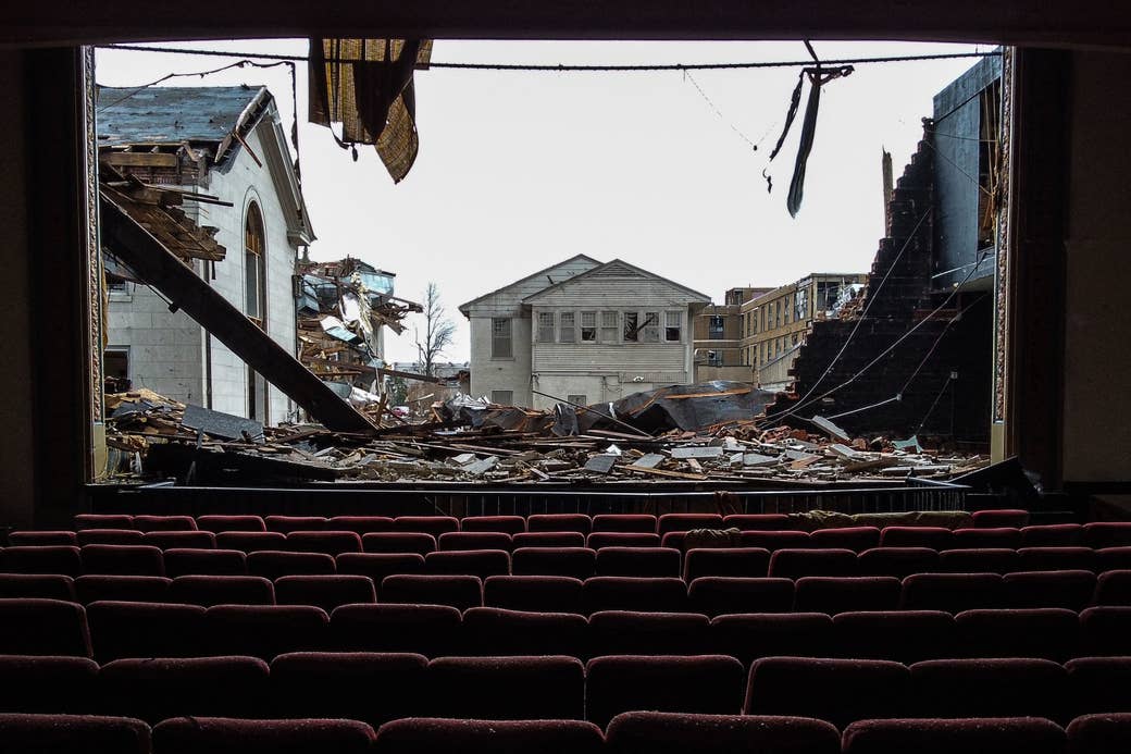 A movie theater with the screen ripped off to show destruction and houses 