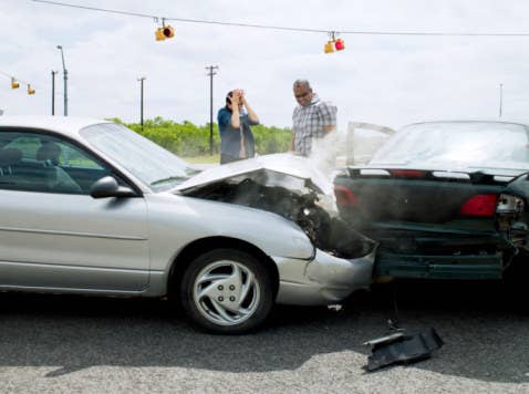 Two people stand near their cars after a fender bender.