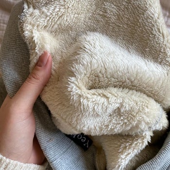 a reviewer holding the pants and showing the fluffy interior lining