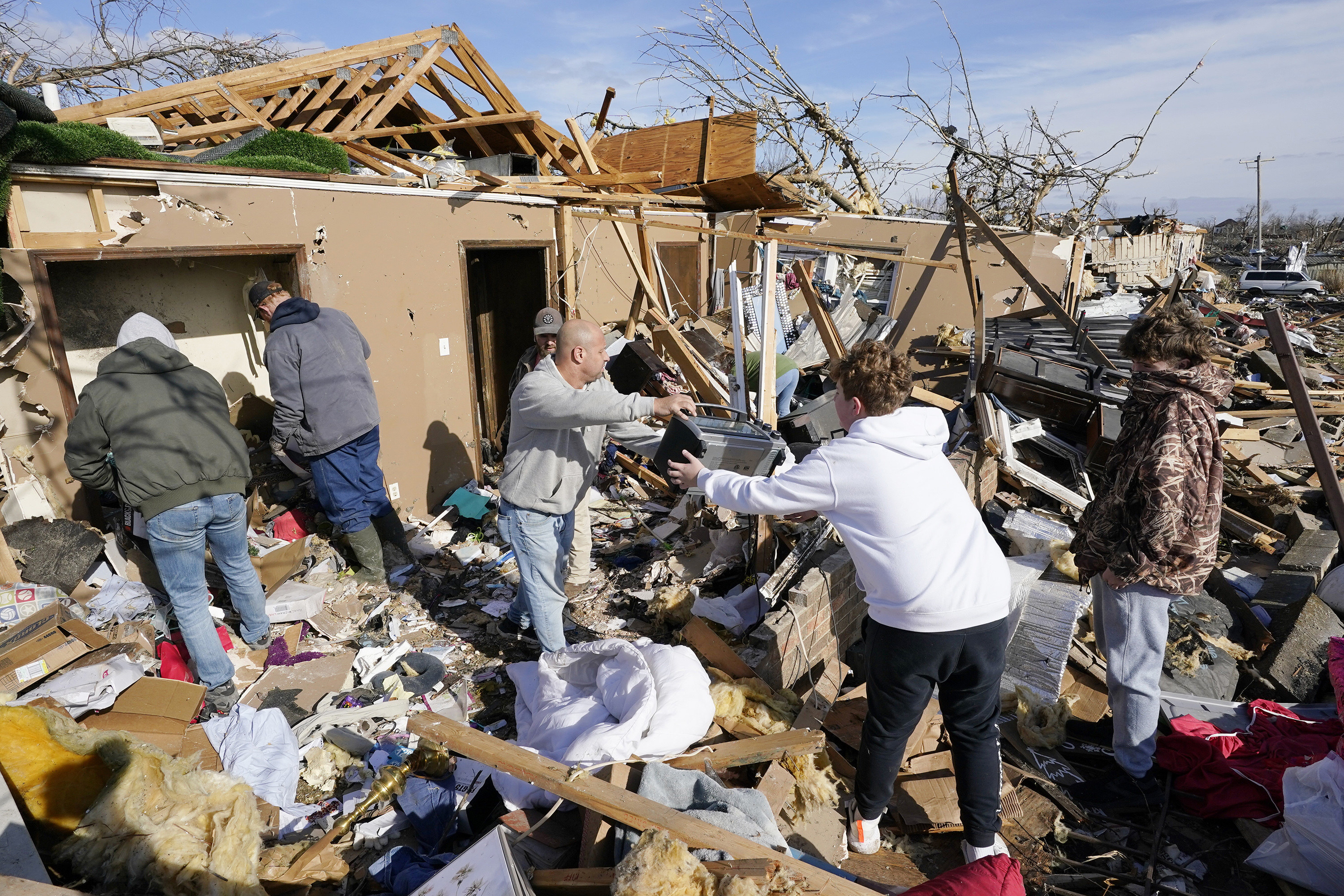 A group of people helping to pass items over debris at a destroyed house 