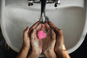 Two pairs of hand use a heart-shaped soap to wash their hands