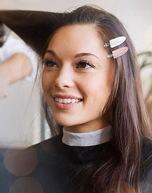 A person with two hair clips in their hair while they get their makeup done