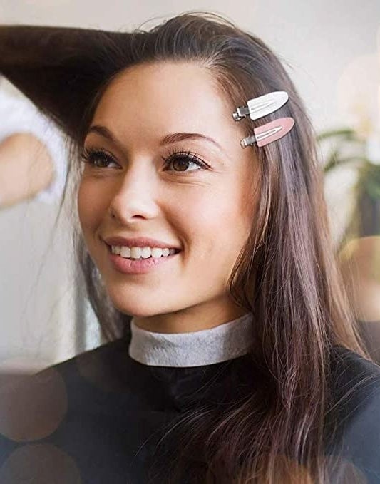 A person with two hair clips in their hair while they get their makeup done