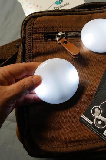a reviewer showing the size of the light on top of their backpack