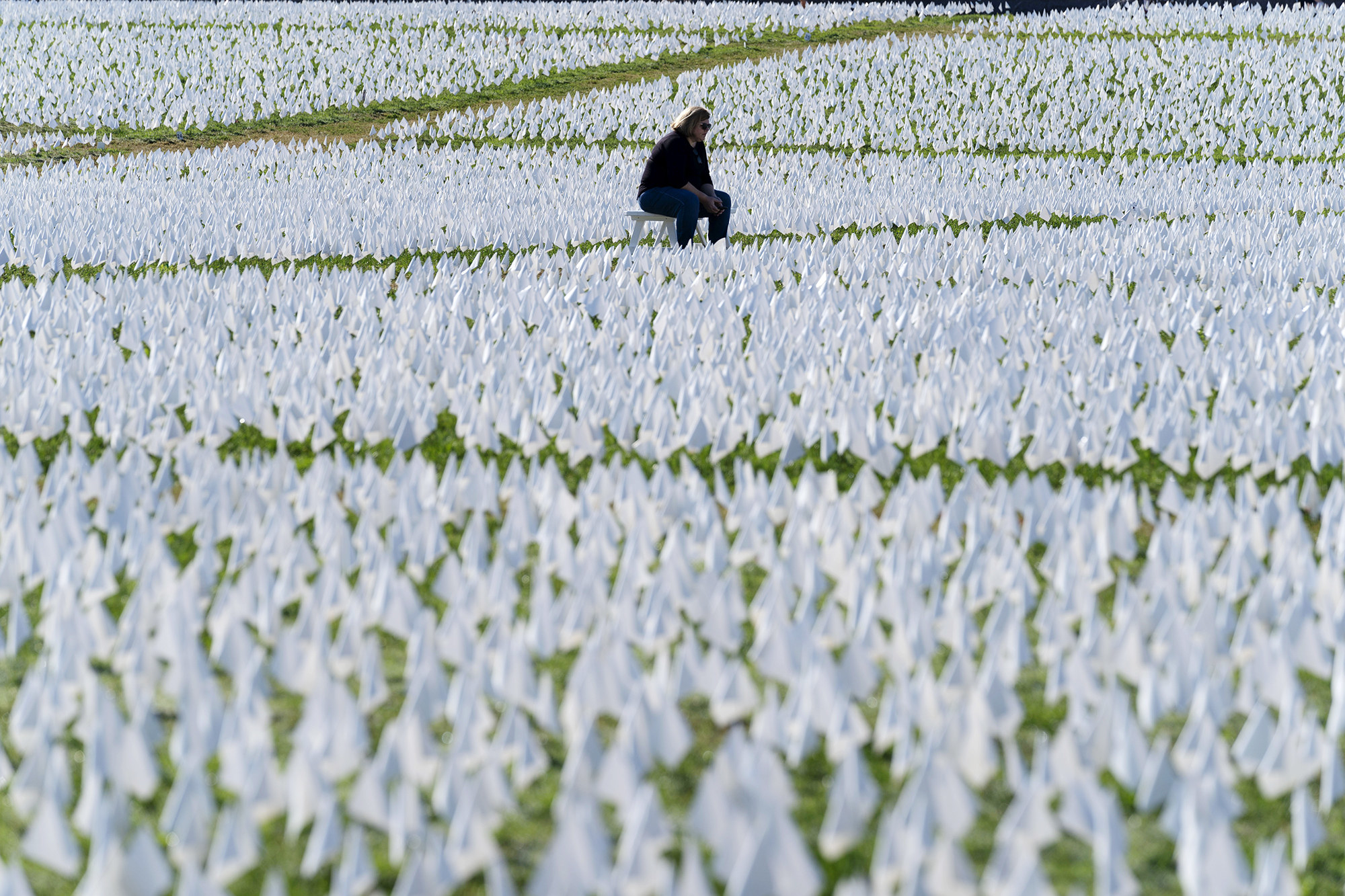 Thousands of flags form a field of white with a person sitting in the middle