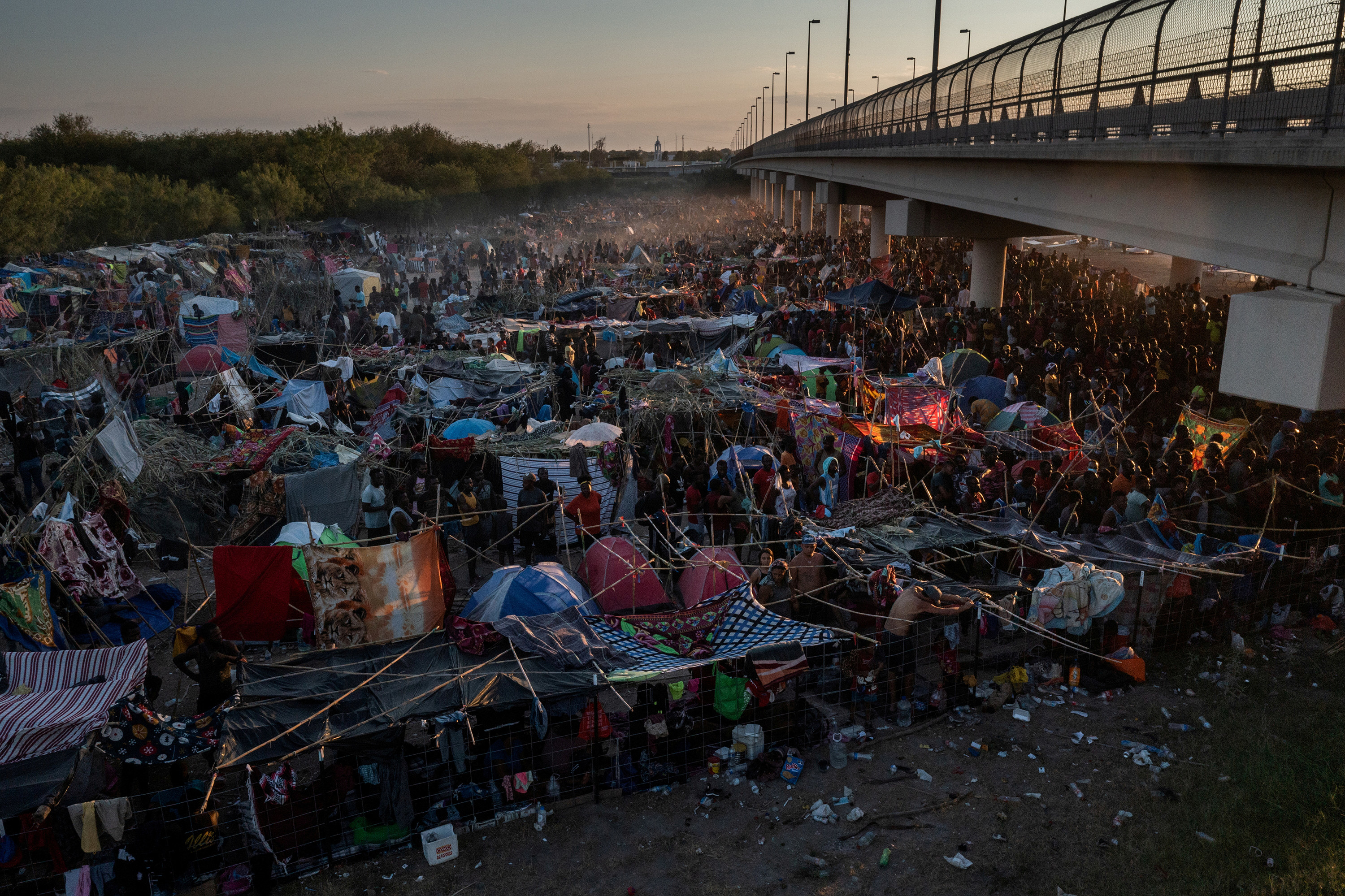 People seen living under makeshift structures made of blankets and sticks under a bridge