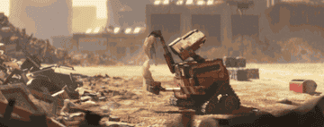 GIF of Wall-E finding a bra in a rubble pile and trying it on over eyes