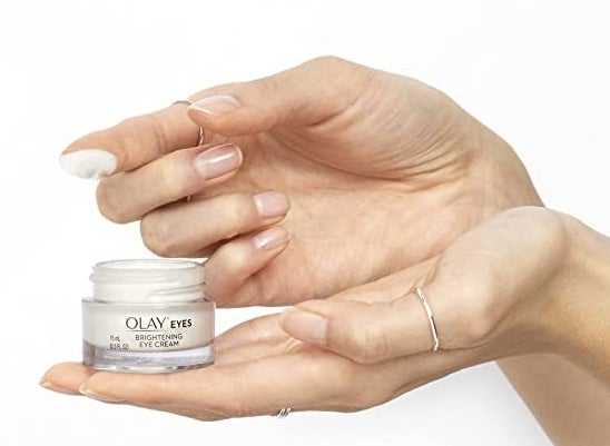 Model holding Olay eye cream with the product on their finger