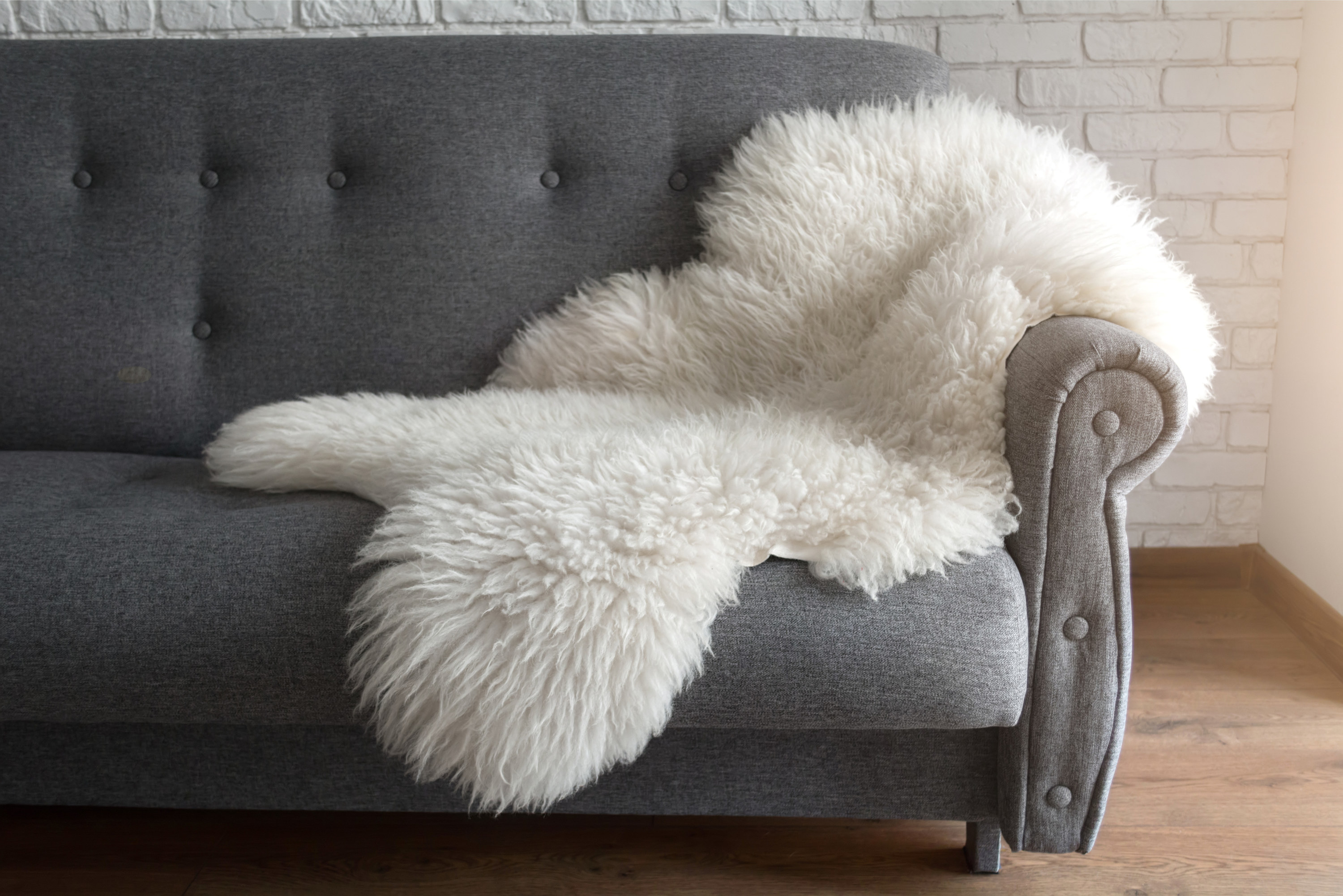 White faux animal hide rug draped over a gray couch
