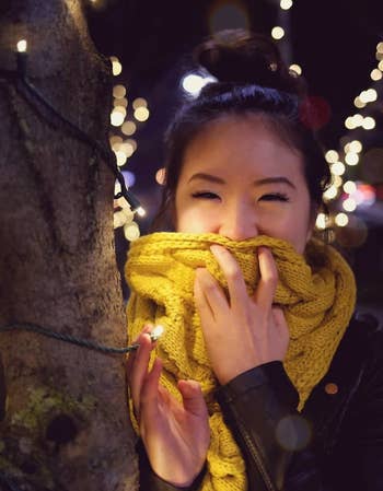 Reviewer wearing the yellow scarf next to a tree lit with holiday lights