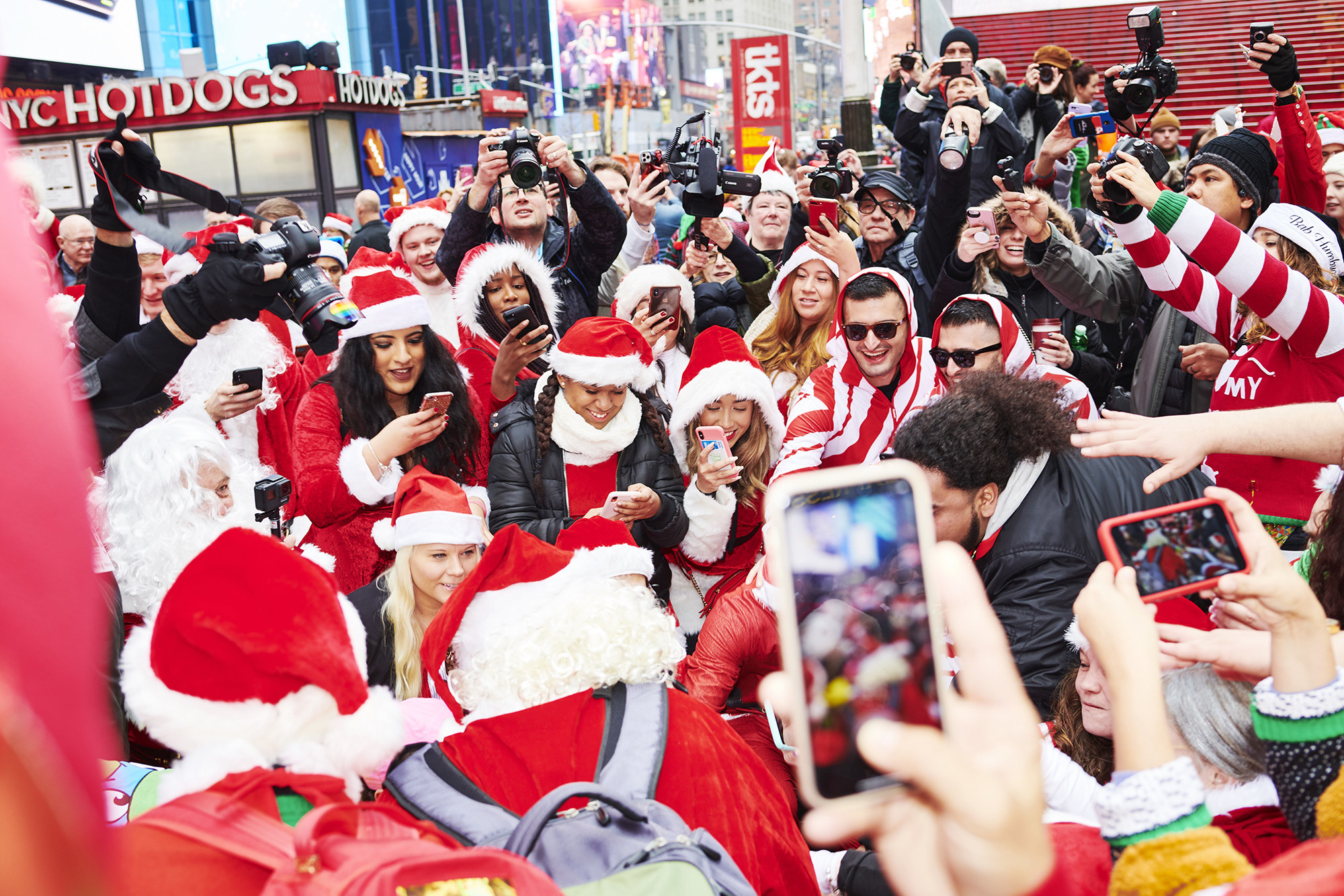People dressed as Santa Claus gather at Father Duffy Square for SantaCon in New York City as a crowd of non-Santas take pictures behind them