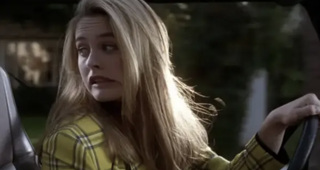 Alicia Silverstone behind the wheel and grimacing with her head turned