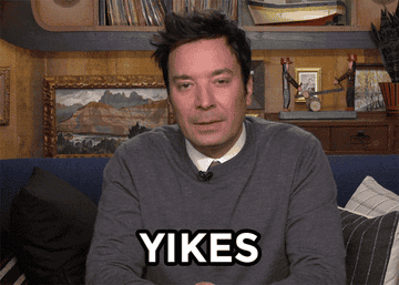Jimmy Fallon wearing a grey shirt sitting on a couch saying, &quot;Yikes&quot;