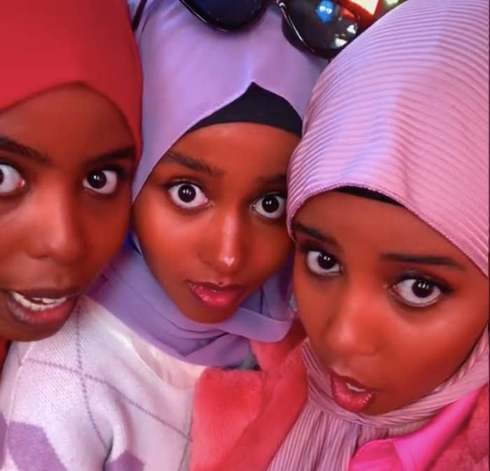 Three young women wearing bright colored hijabs pose for a selfie