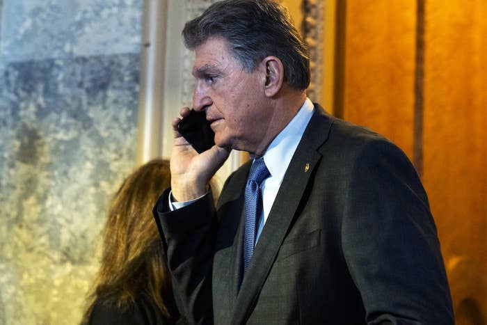 Joe Manchin, wearing a suit, with a phone up to his ear