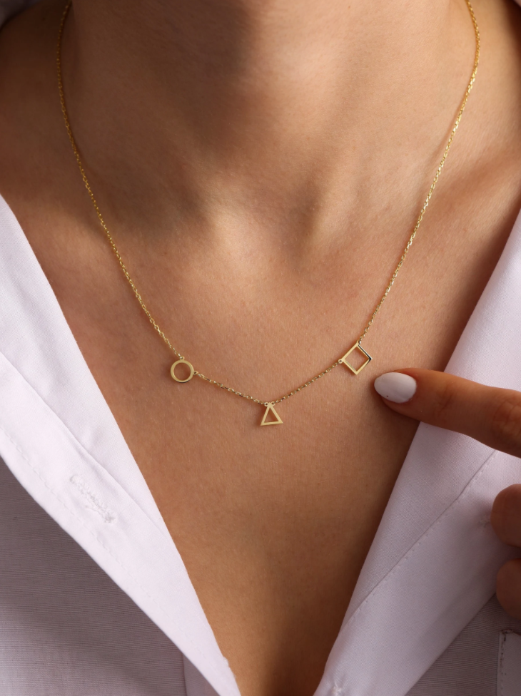 a delicate gold chain necklace with a circle, triangle, and square pendants